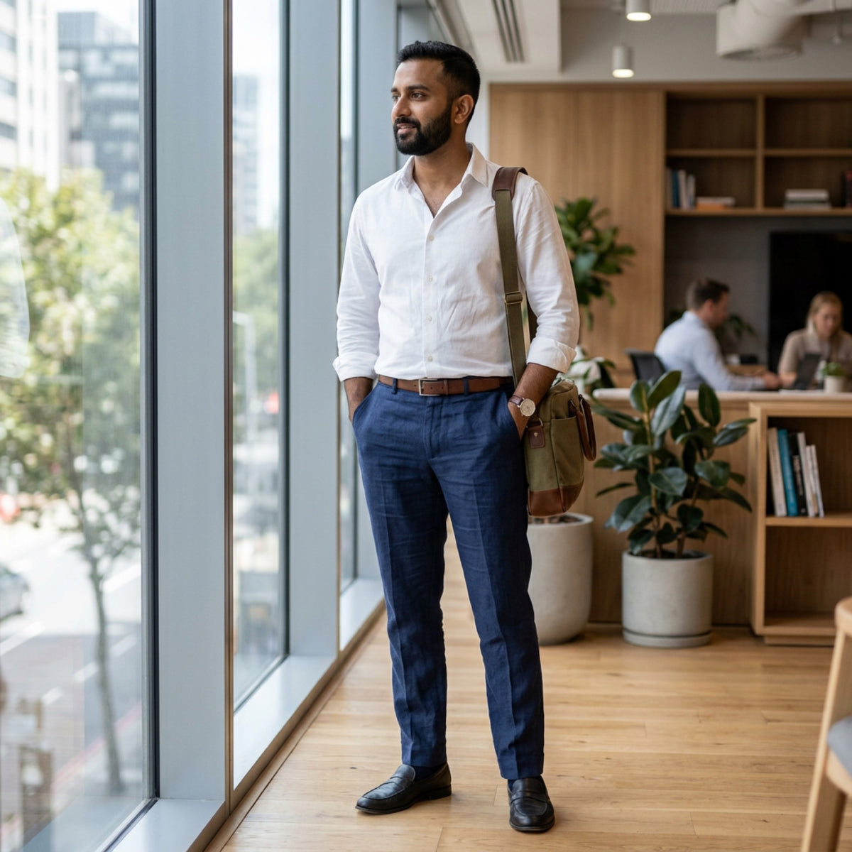 Man in a white shirt and navy trousers in a bright office